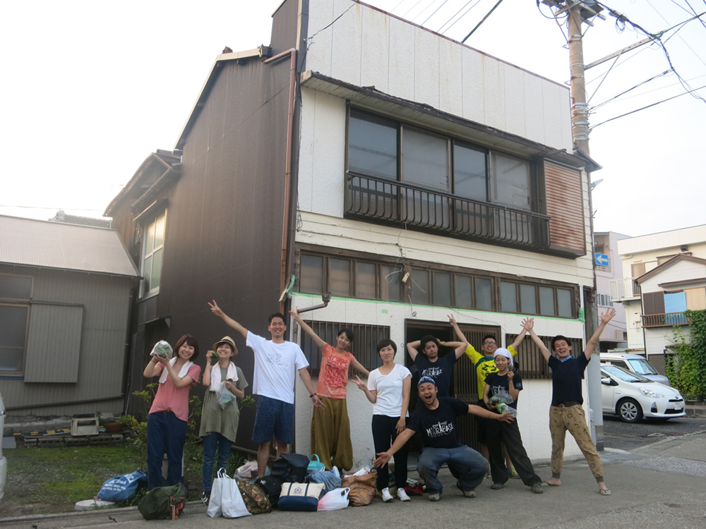改修前の建物外観とセルフリノベーションに参加したメンバー。建物はマグロ漁船の乗組員たちの宿泊所として使われていたそう。